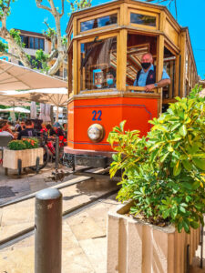 A tram driving through the centre of soller, a beautiful village that features in the ultimate mallorca travel guide