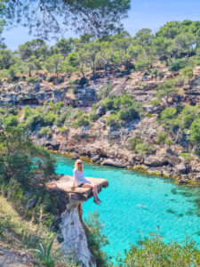 sitting on a rock over looking the blue crystal waters a perfect destination in the ultimate mallorca travel guide